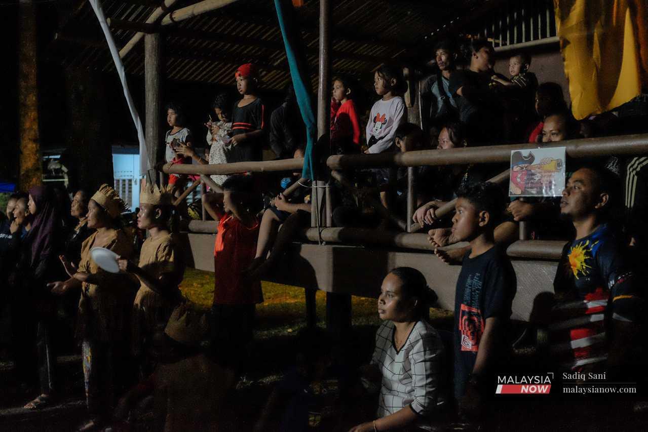 Penduduk kampung yang lain duduk di bahagian tepi pentas untuk menonton persembahan.