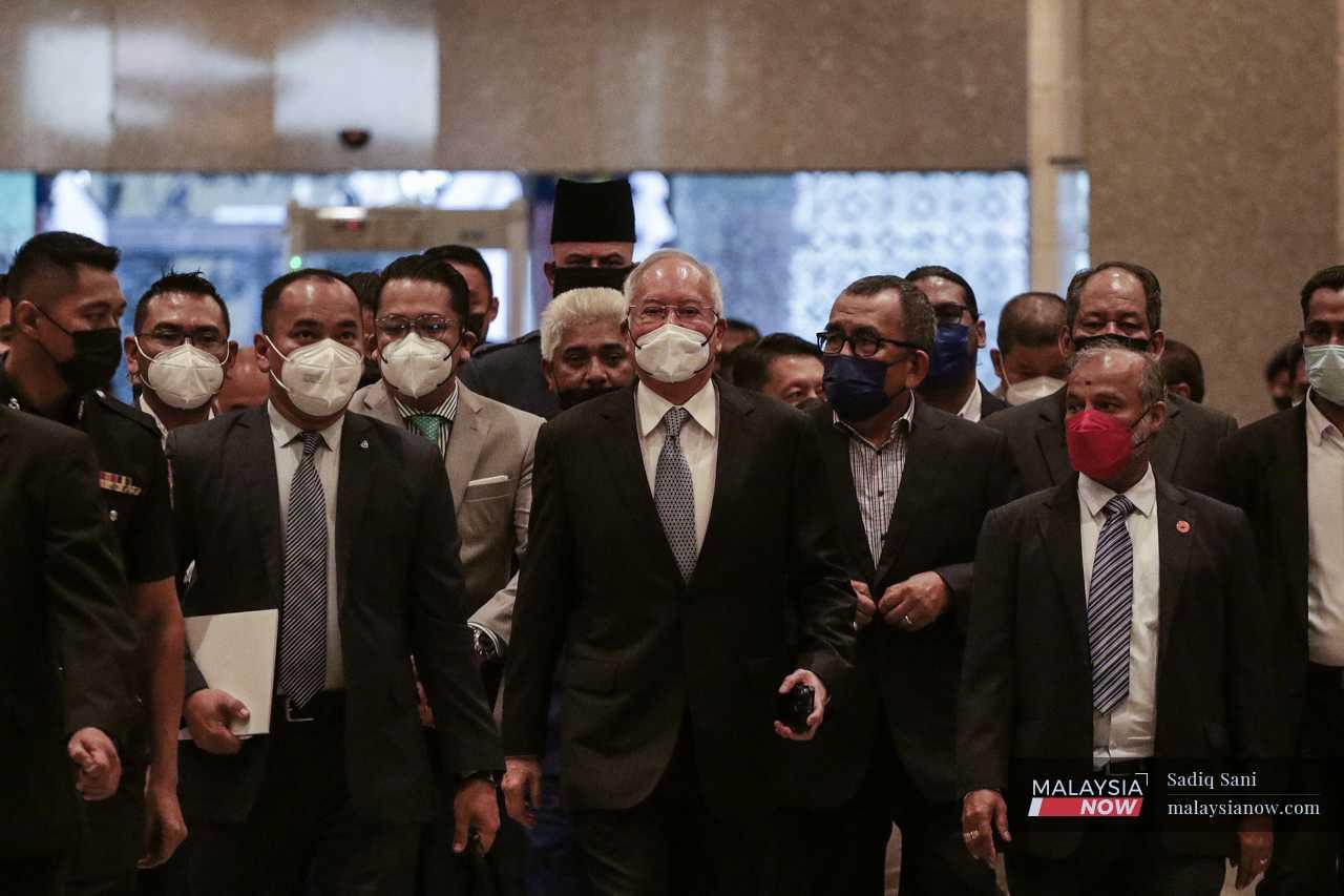 Former prime minister Najib Razak (centre) flanked by his officers as he arrives at the Palace of Justice in Putrajaya for the final leg of his SRC International appeal. 