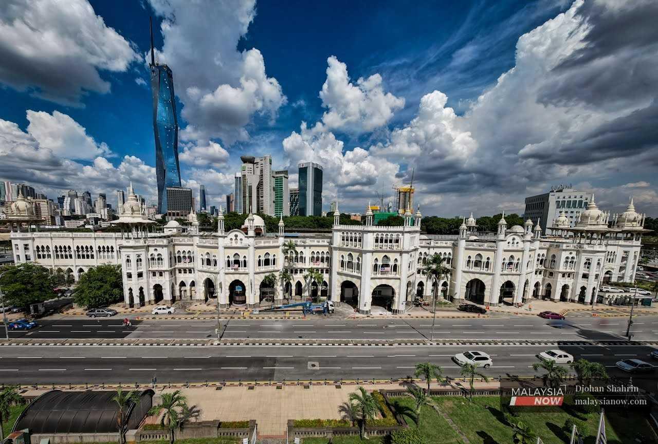 The Kuala Lumpur KTM station, a long, low building with a unique architecture combining Eastern and Western designs, stands against a backdrop of taller, more modern buildings such as the Warisan Merdeka Tower in Jalan Sultan Hishamuddin in the capital city. 
