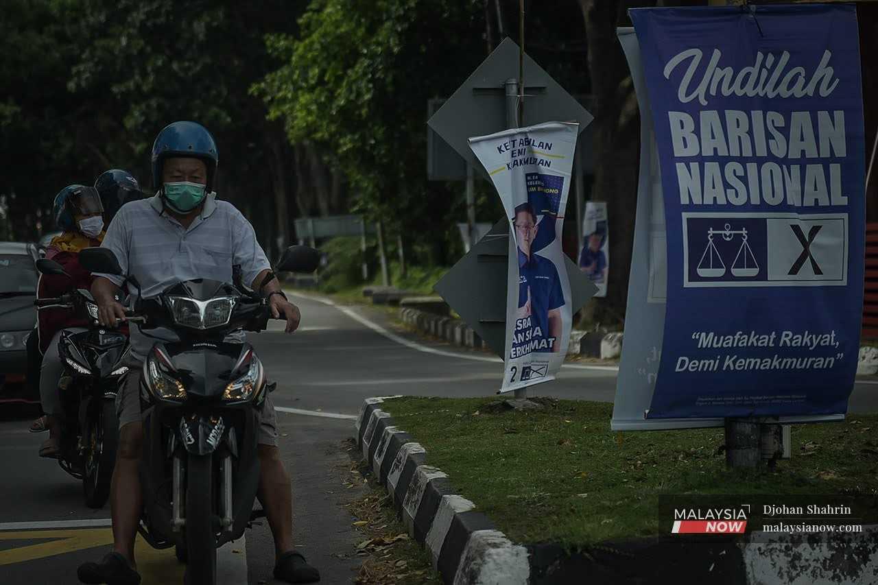 Seorang penunggang motorsikal menunggu lampu merah di sebuah selokah yang digantung bendera Barisan Nasional menjelang Pilihan Raya Negeri Melaka tahun lalu.