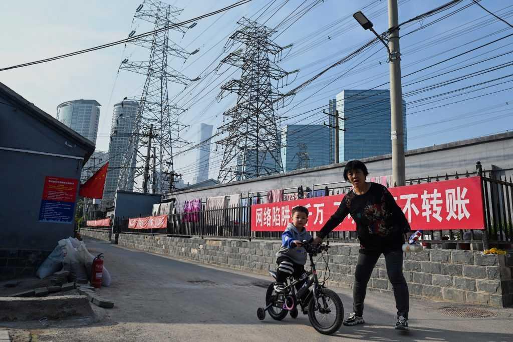 A woman guides a boy learning to cycle below power lines in Beijing on Oct 13, 2021. Photo: AFP 