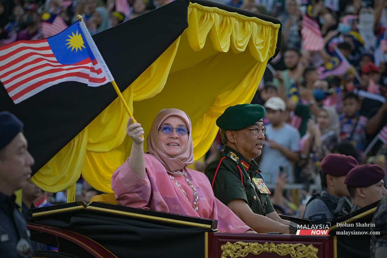 Yang di-Pertuan Agong Sultan Abdullah Sultan Ahmad Shah dan Raja Permaisuri Agong Tunku Azizah Aminah Maimunah Iskandariah yang turut sama menyertai perarakan mengibarkan Jalur Gemilang ke arah orang ramai.