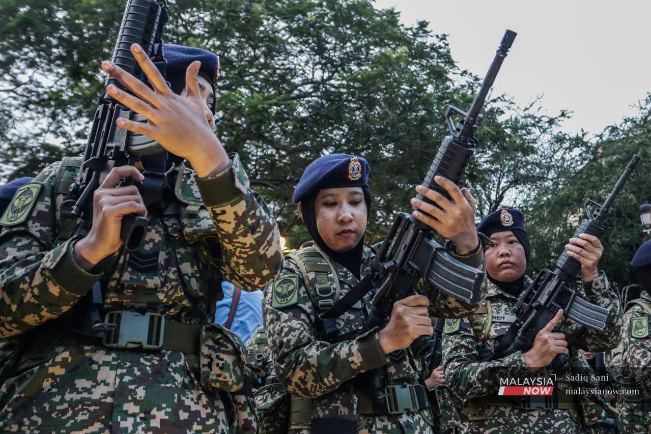Anggota tentera wanita dari pasukan Rejimen Logistik Komando Tentera Darat memeriksa senjata mereka sebelum perbarisan bermula.