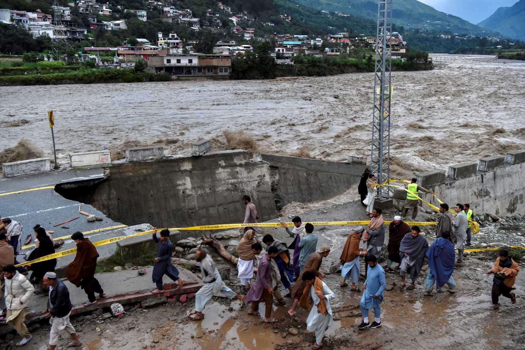 People gather in front of a road damaged by flood waters following heavy monsoon rains in Madian area in Pakistan's northern Swat Valley on Aug 27. Photo: AFP