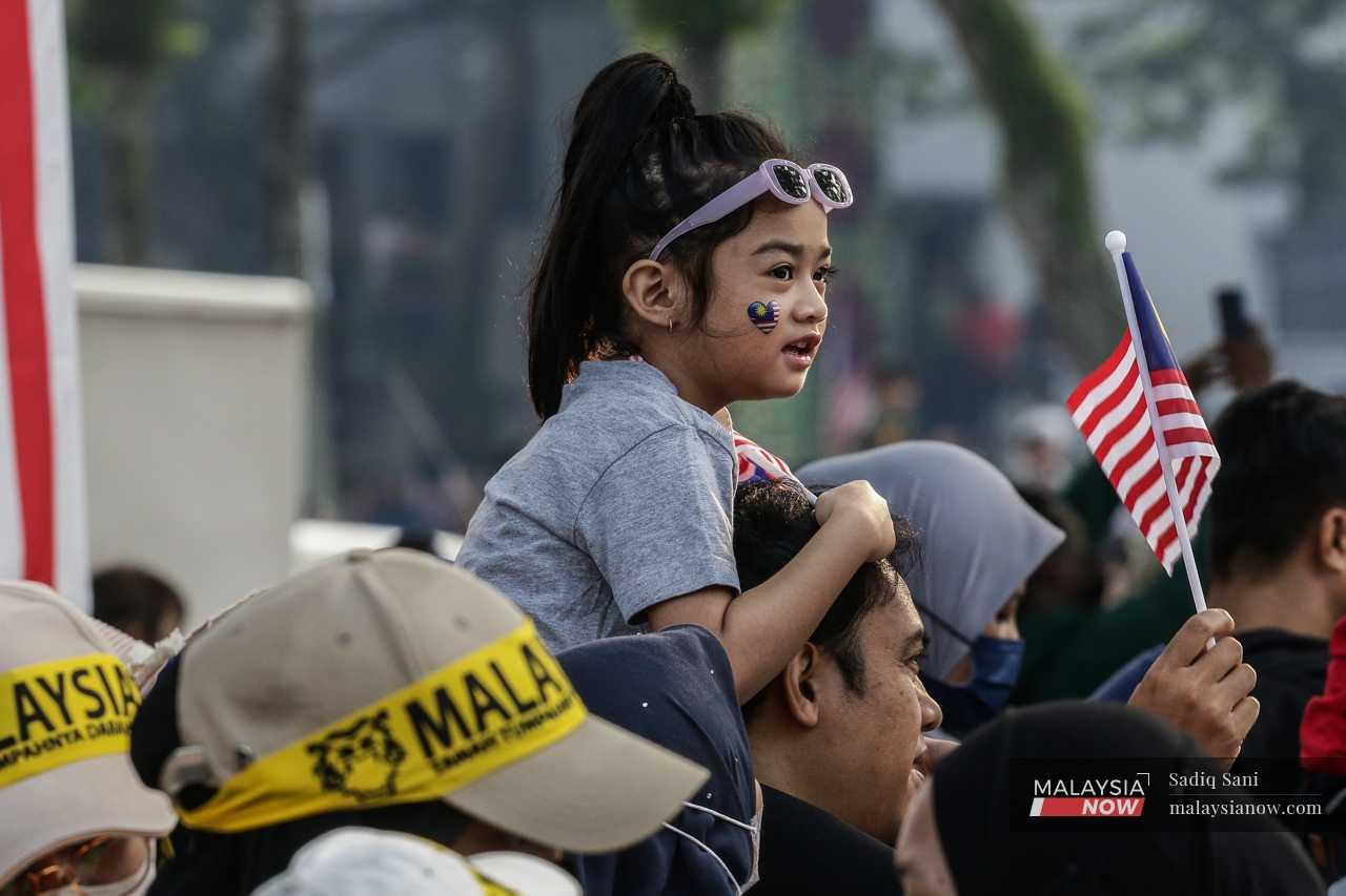 A girl sits on her father's shoulders to get a better view of the parade. 
