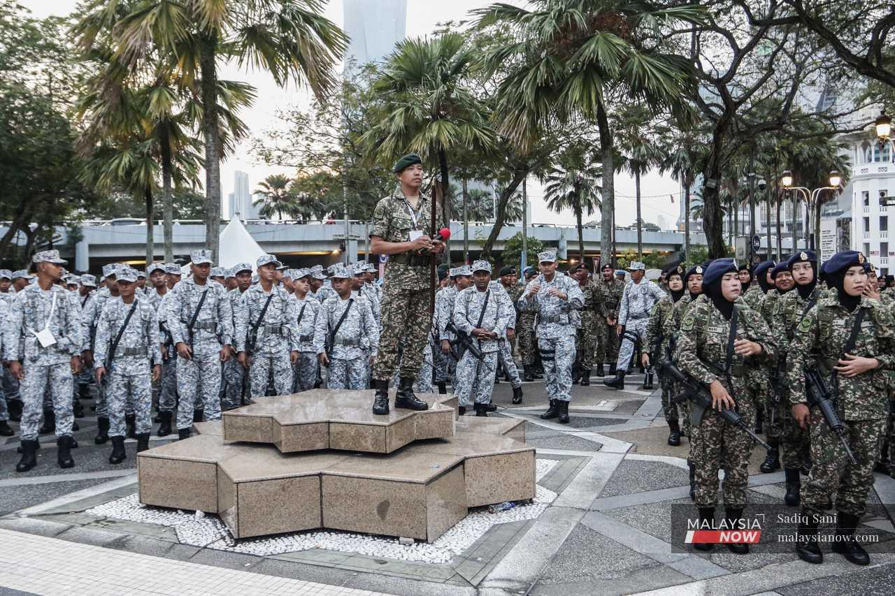 An army officer stands on a marble bench to gather his personnel for a briefing before the parade. 