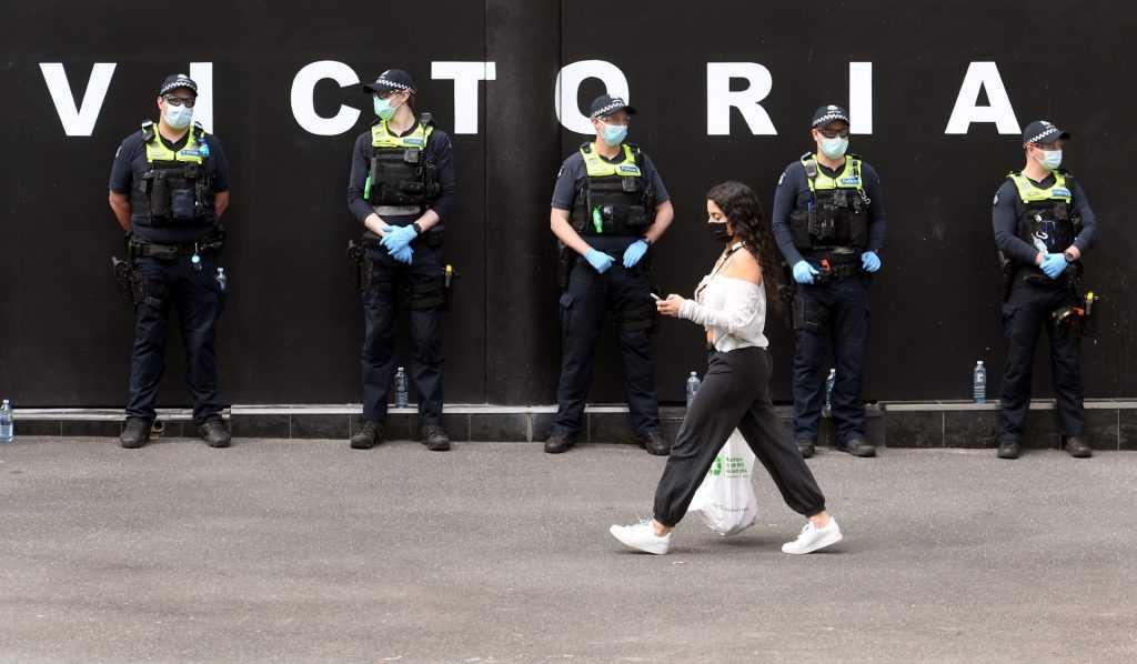 A woman carries her shopping while police officers stand guard on a Melbourne street on Sept 29, 2021. Photo: AFP