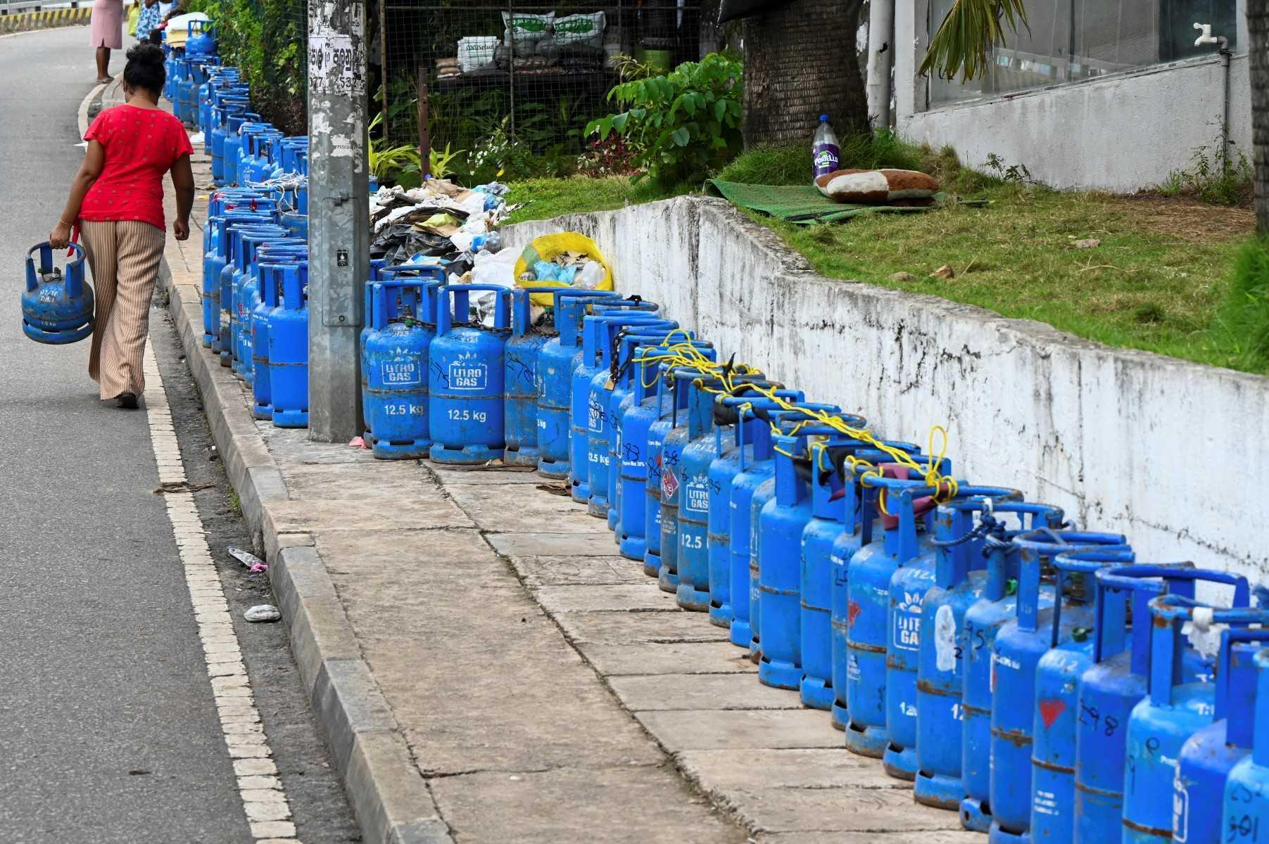 A woman carrying a liquefied petroleum gas cylinder walks past others placed by people queueing to buy LPG during shortages of essentials across Sri Lanka, in Colombo on June 10. Photo: AFP