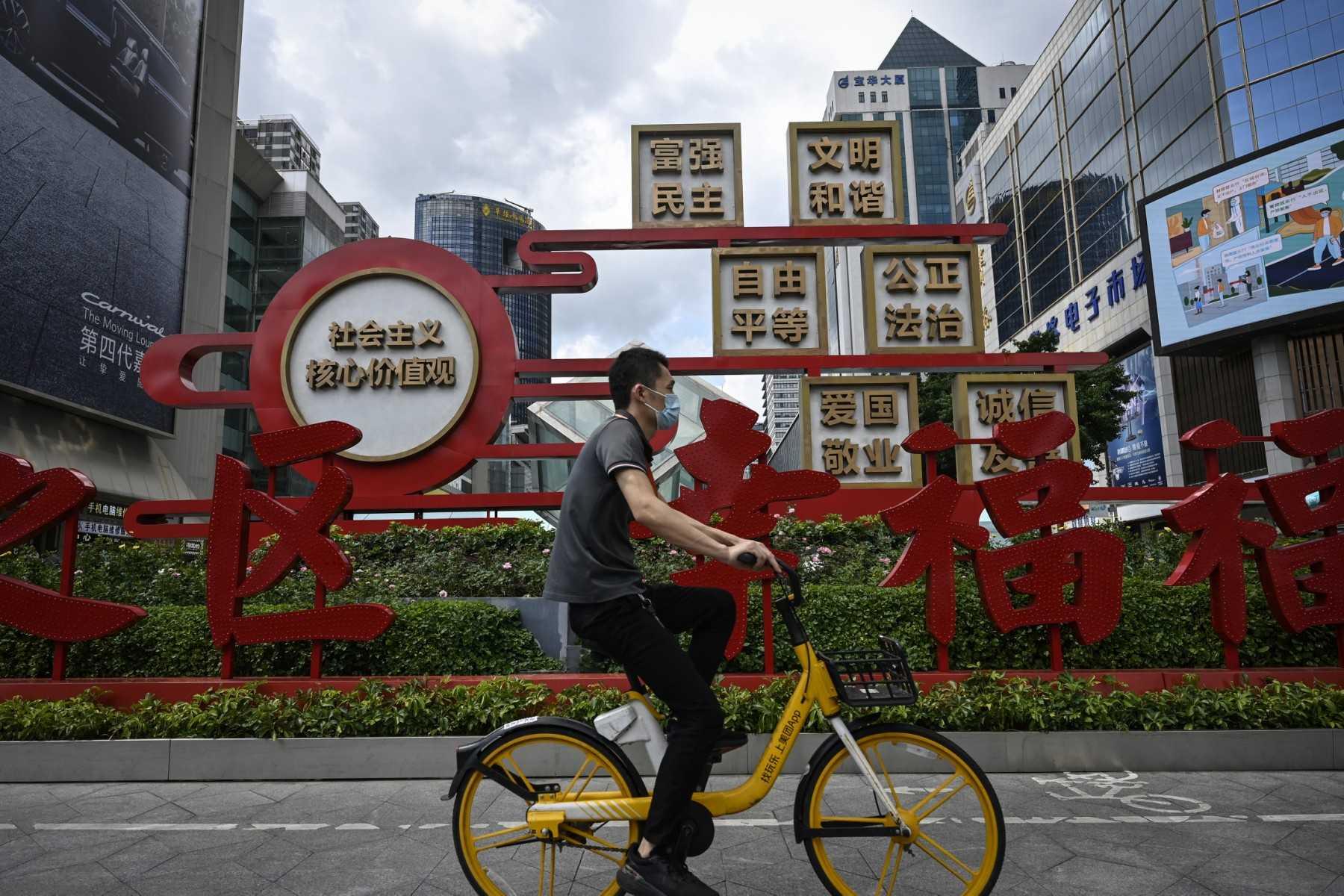 This photo taken on July 12 shows a man riding past a sign displaying a propaganda slogan of socialist core values in Shenzhen in China's southern Guangdong province. Photo: AFP