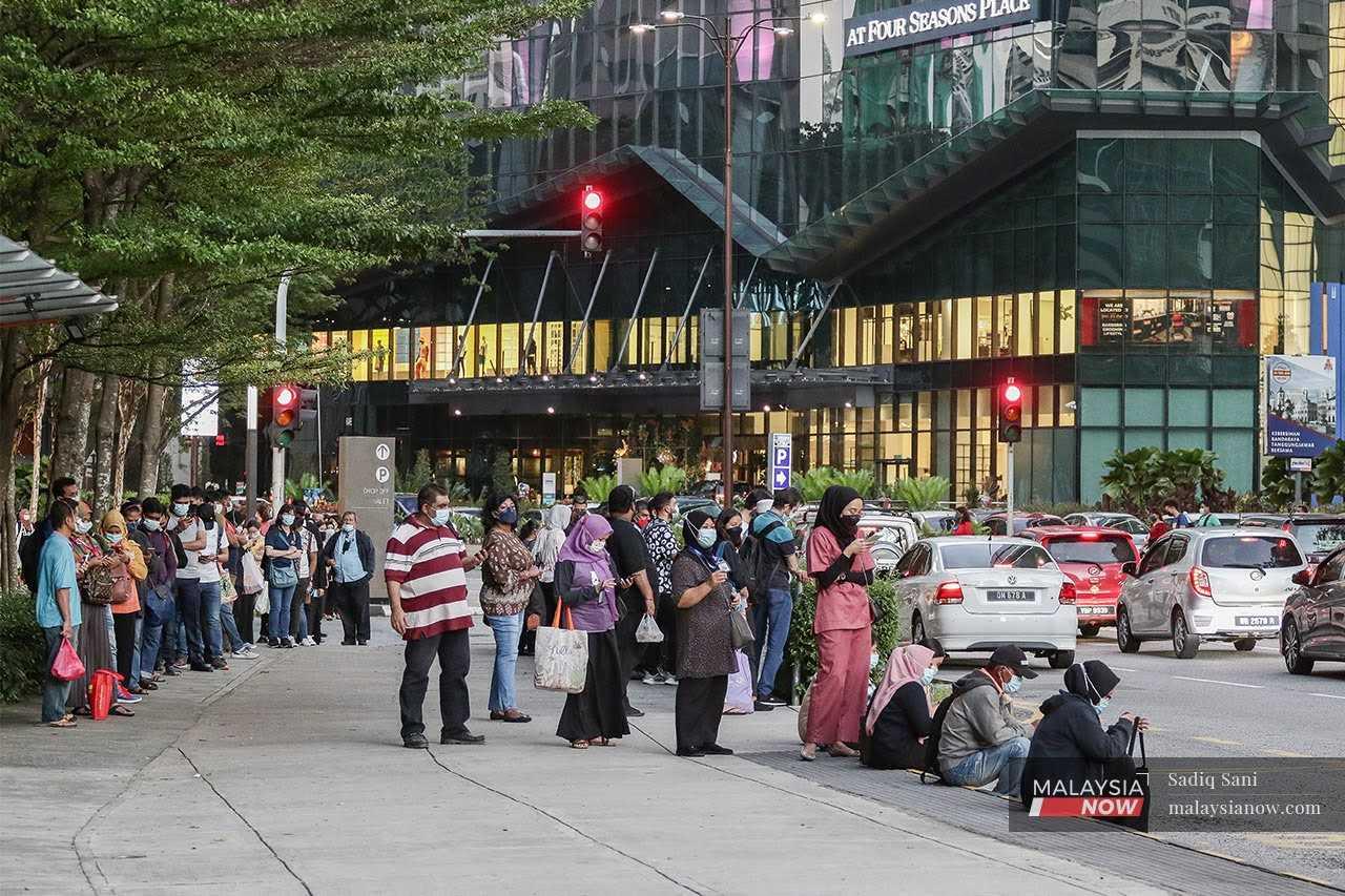 People wait for the bus at a bus stop in Jalan Ampang, in the capital city of Kuala Lumpur. 
