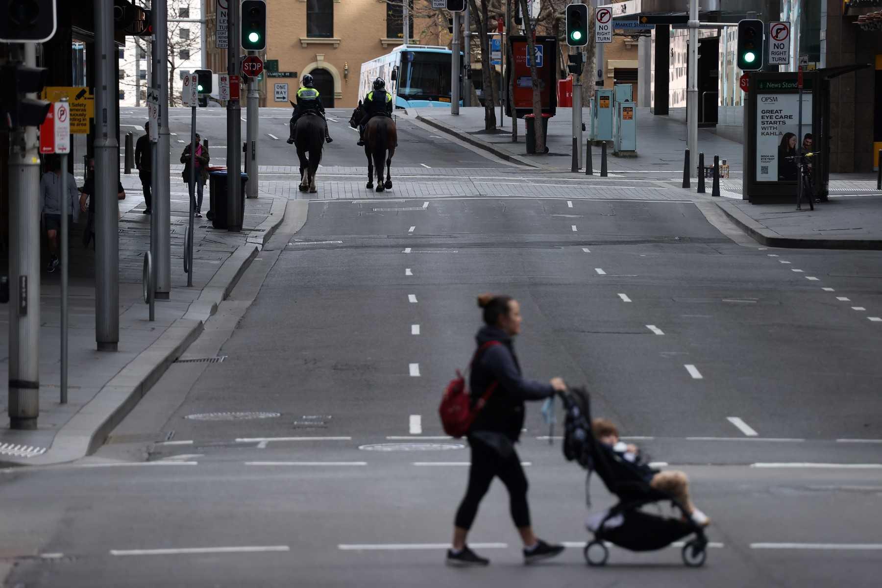 A woman makes her way through a quiet street in the central business district of Sydney on July 31, 2021. Photo: AFP 