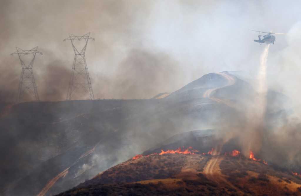 A firefighting helicopter performs a water drop as the Route Fire burns on Aug 31, near Castaic, California. Photo: AFP 