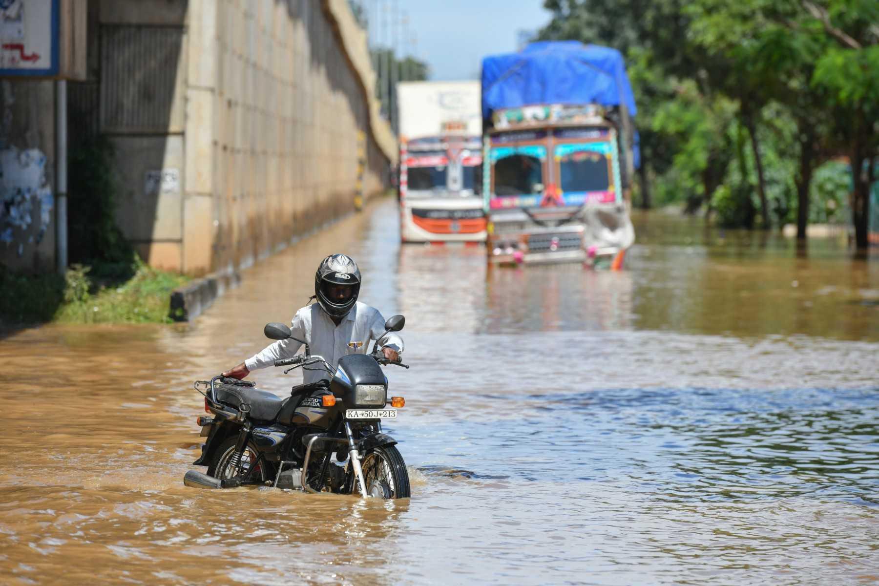 Motorists and trucks wade through a street after heavy monsoon rains in Bangalore on Sept 5. Photo: AFP