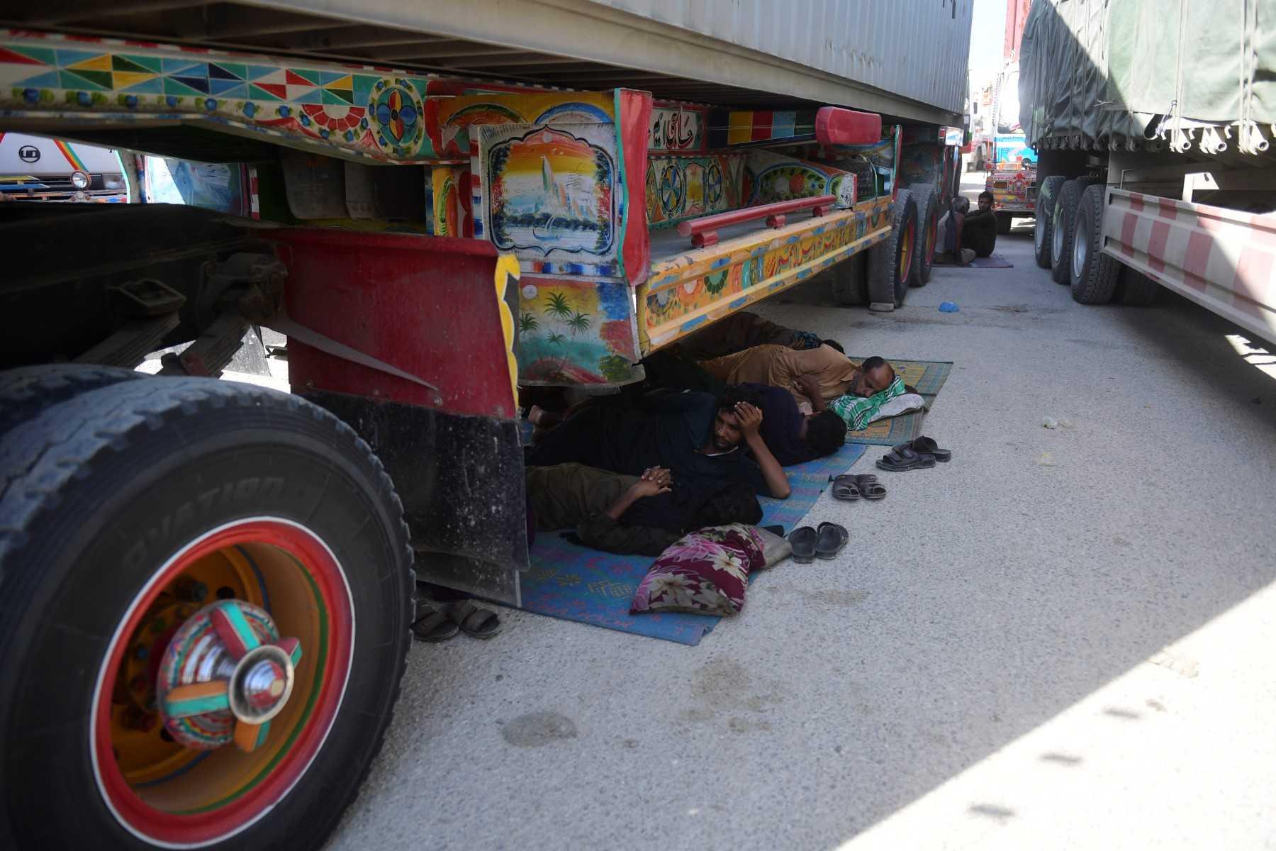 Stranded truck drivers take nap along a national highway damaged by flooding following heavy monsoon rains in Kandiaro area, some 100km from Sukkur, Sindh province, on Sept 2. Photo: AFP