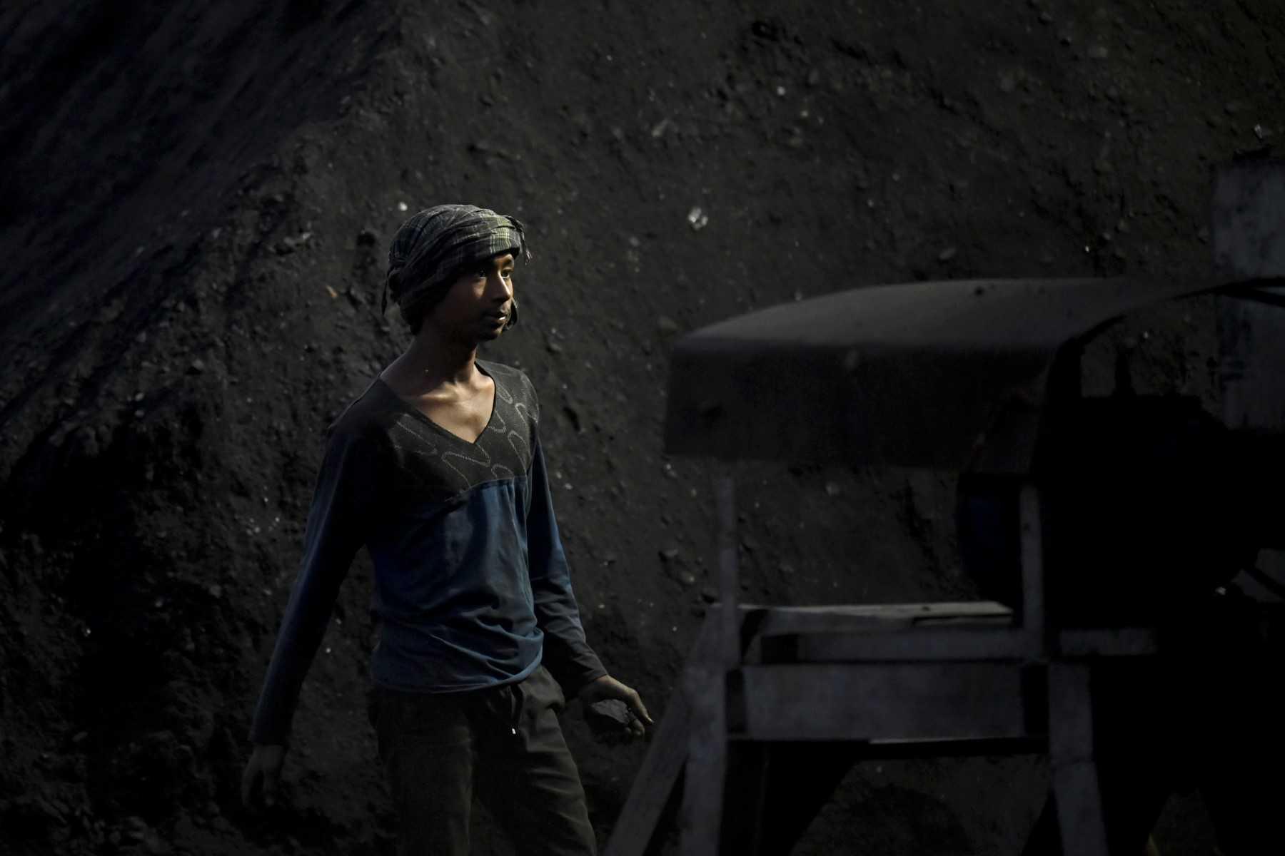 In this photograph taken on April 26, a labourer stands next to a heap of coal in Dolike village on the outskirts of Jalandhar in India's Punjab state. Photo: AFP 