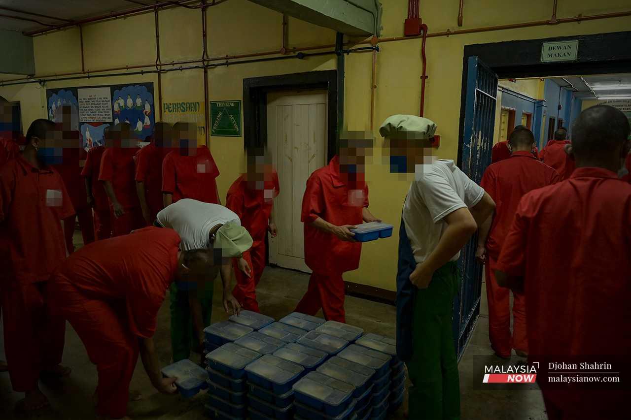 One by one, the prisoners accept their food, thanking those on duty as they walk past. 
