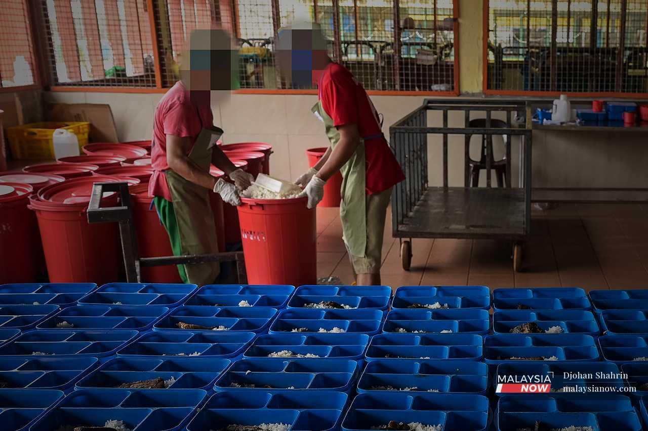 Two others prepare to scoop out white rice from huge plastic buckets. 