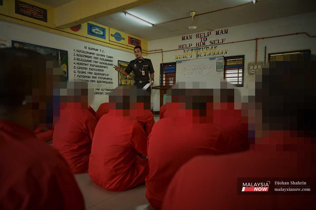 A prison officer speaks to drug offenders during an 'encounter group' session in the rehabilitation wing. 
