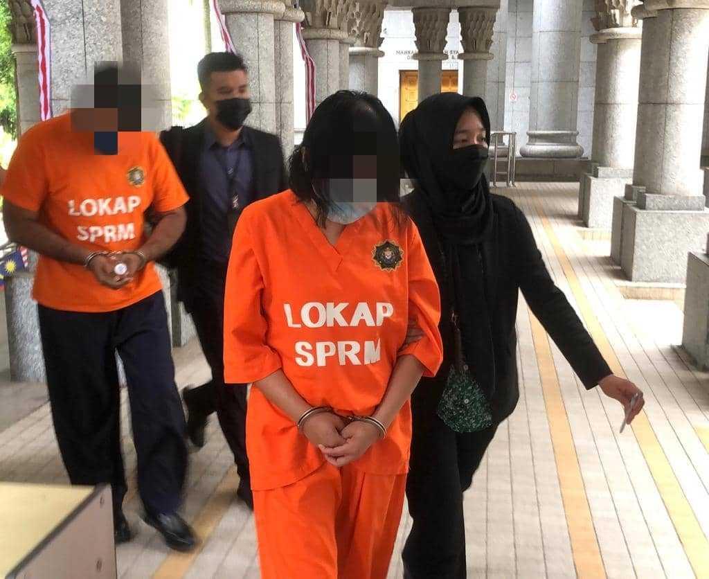 Two suspects believed to be involved in an RM10 million bribery case are led out of the Putrajaya Magistrate's Court today. 
