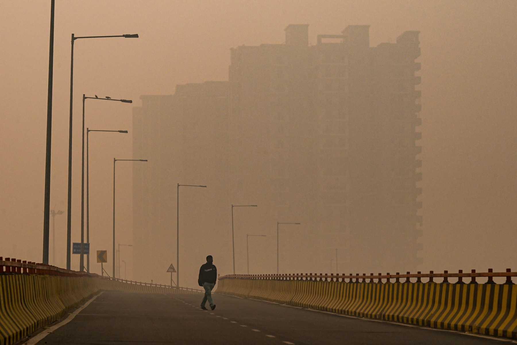 A pedestrian walks along a flyover amid smoggy conditions in Ghaziabad, India, on Nov 5, 2021. Photo: AFP