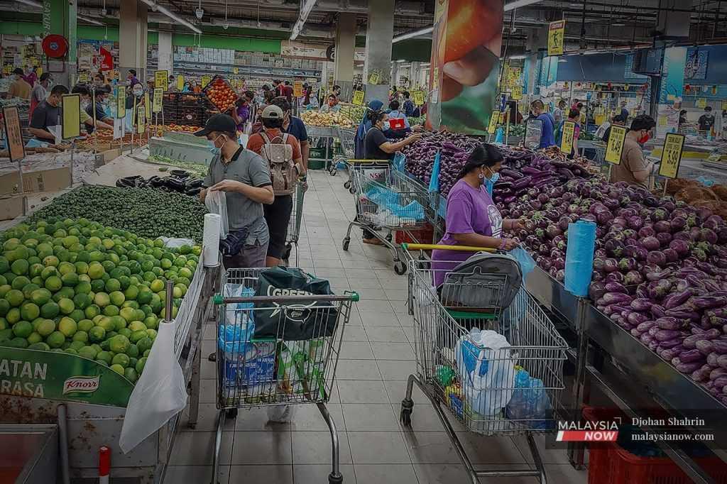 People wearing face masks shop for groceries at a supermarket in Kuala Lumpur.