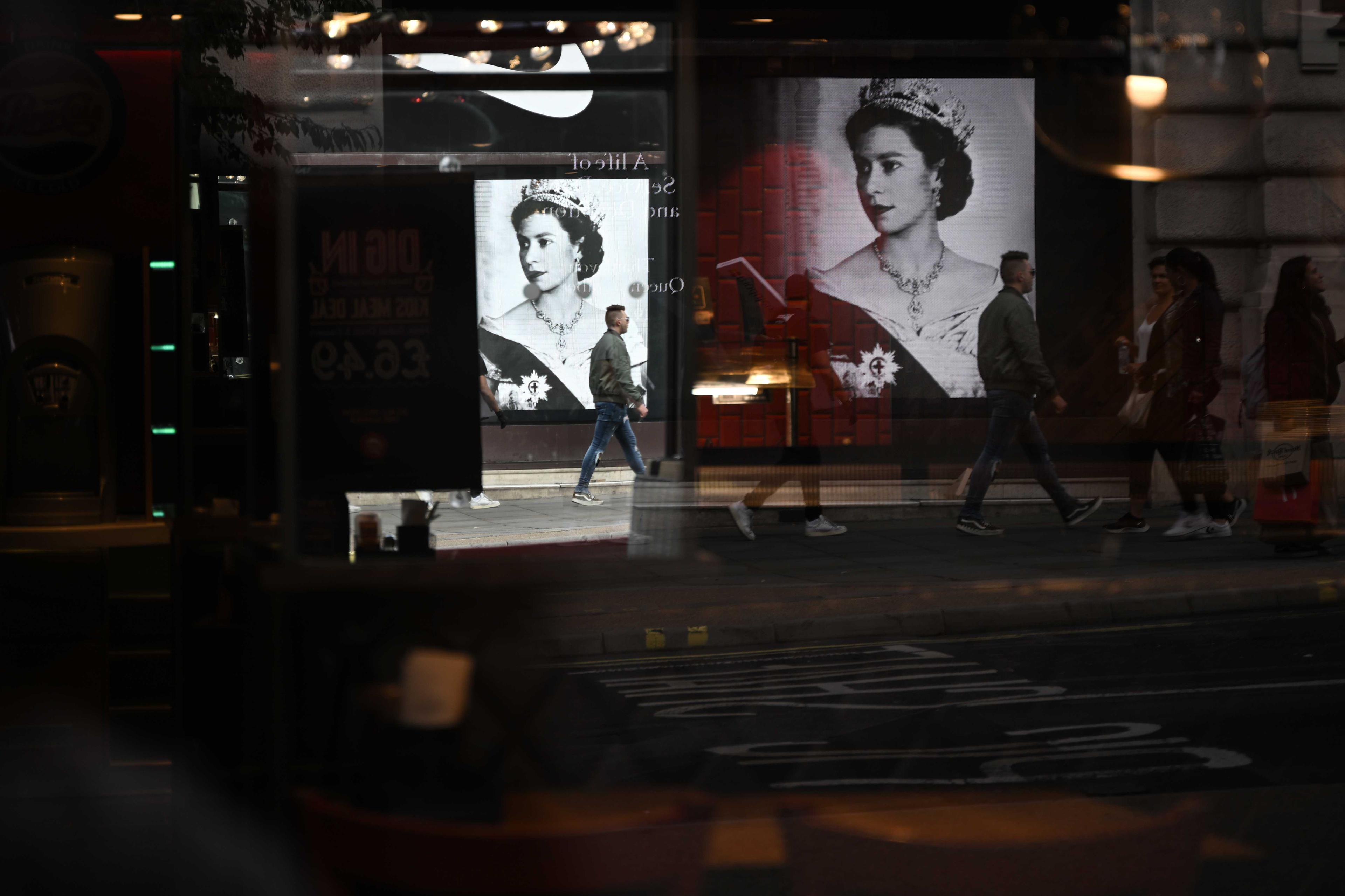 Pedestrians walk past a portrait of Britain's Queen Elizabeth II in London on Sept 11. Photo: AFP