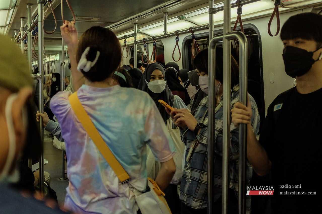 Commuters on an LRT heading to the Kuala Lumpur city centre continue to wear face masks as stipulated by the government.  
