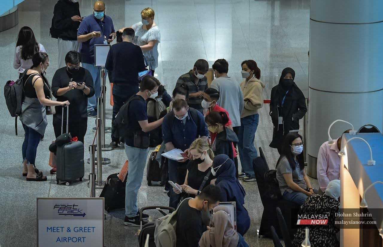 Travellers mingle at the help desk at KLIA in Sepang following the reopening of Malaysia's international borders.