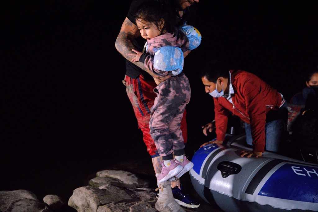 A smuggler lifts an immigrant child into the US after crossing the Rio Grande on April 15, 2021 in Roma, Texas. Photo: AFP 
