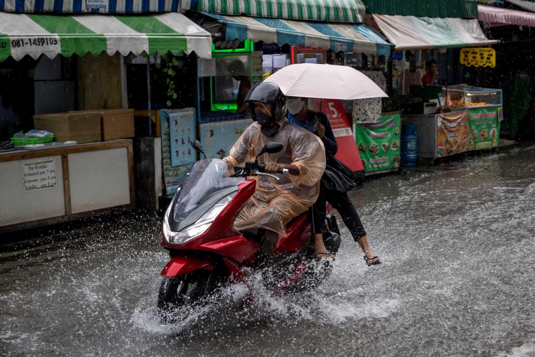 Penunggang motorsikal meredah banjir dan hujan lebat di kawasan pasar di Bangkok pada 13 September 2022. Gambar: AFP
