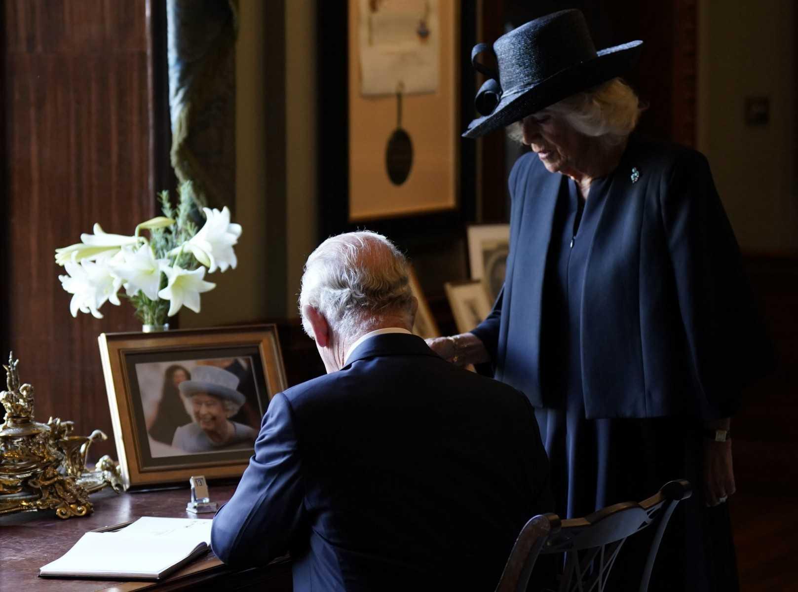 Britain's Camilla, Queen Consort (right) watches as Britain's King Charles III signs the visitors' book, alongside an image of his late mother Queen Elizabeth II, at Hillsborough Castle in Belfast on Sept 13, during his visit to Northern Ireland. Photo: AFP 