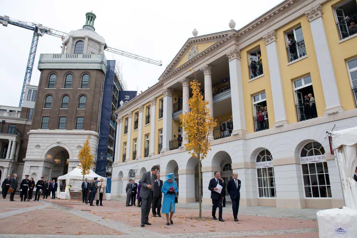 Britain's Queen Elizabeth II (centre) tours the square on a visit to the town of Poundbury, southwest England, on Oct 27, 2016. Poundbury is an experimental new town designed with traditional urban principles championed by Charles, now King of Britain, and built on land owned by the Duchy of Cornwall. Photo: AFP