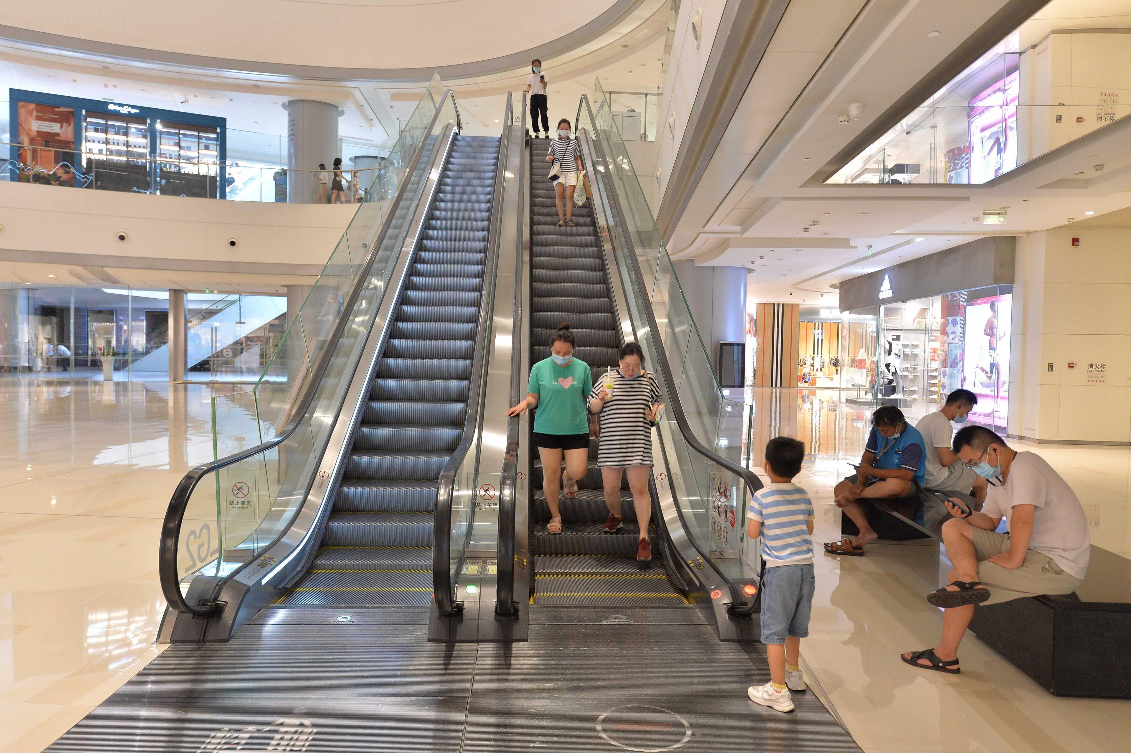 This photo taken on Aug 17, shows people walking down from an escalator at a shopping mall in Chengdu, in China's southwestern Sichuan province. Photo: AFP