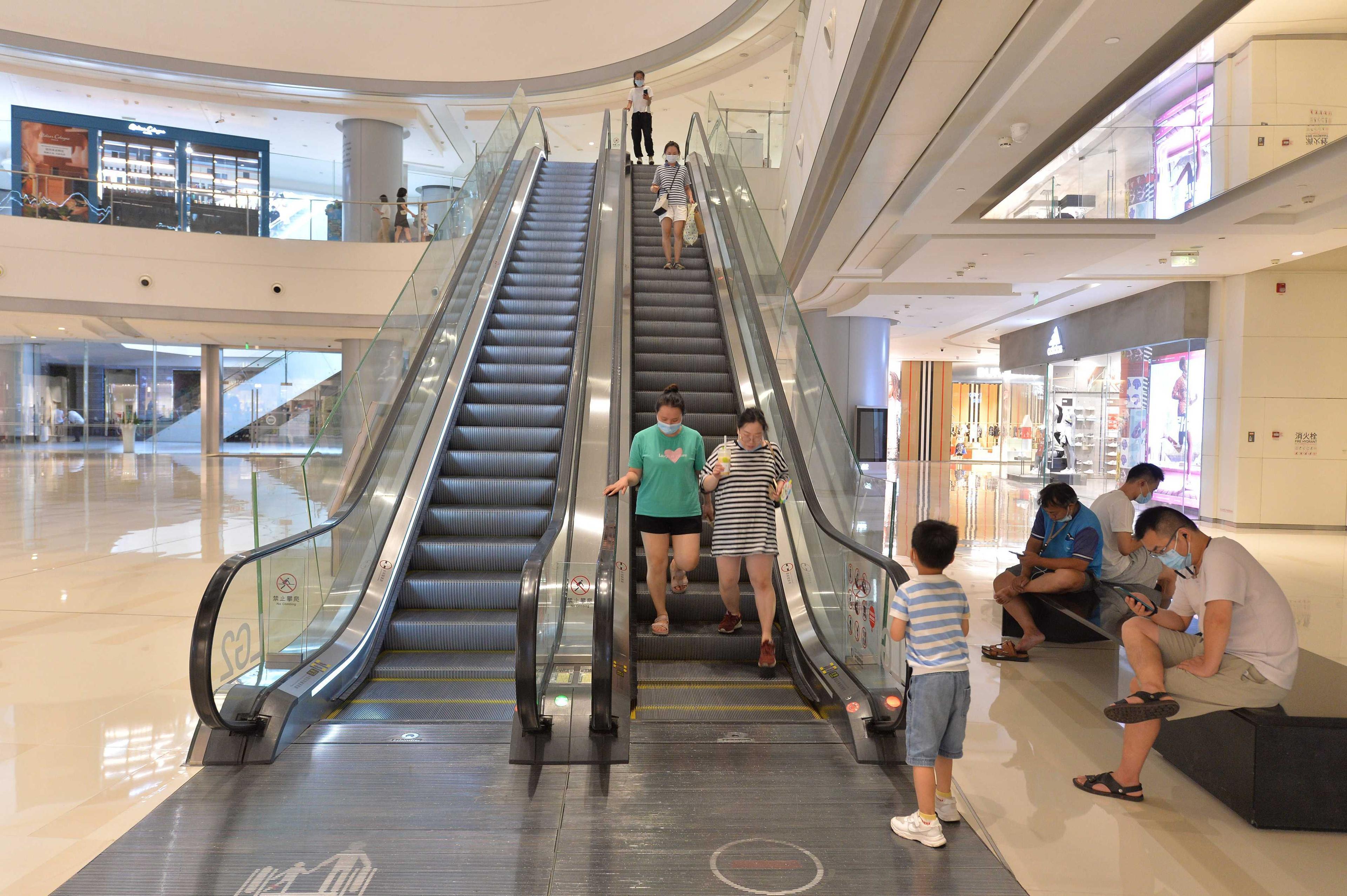 This photo taken on Aug 17, shows people walking down from an escalator at a shopping mall in Chengdu, in China's southwestern Sichuan province. Photo: AFP 