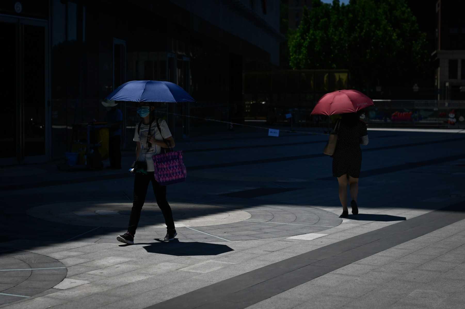 Two women walk with umbrellas to shelter from the sun on a hot day in Beijing on June 24. Photo: AFP 