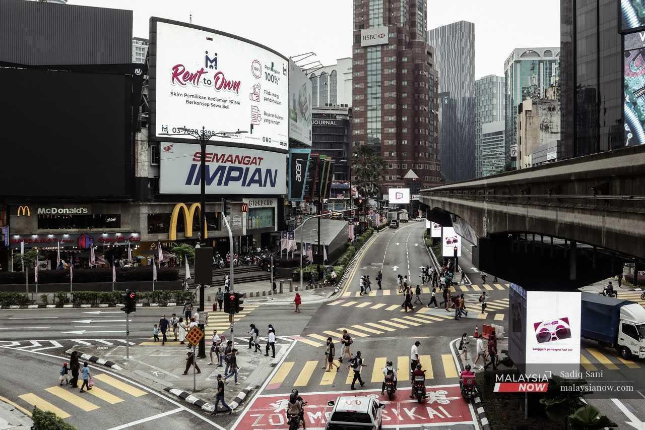 Pedestrians cross the road at a junction in the shopping district of Bukit Bintang in Kuala Lumpur. 