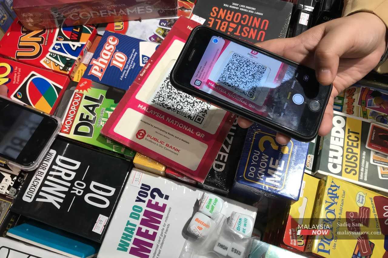 A customer scans a QR code to make an online payment at a souvenir shop in Ipoh.