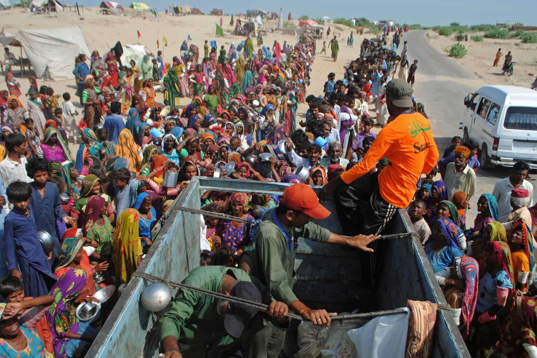 Internally displaced people gather to receive free food near their makeshift camp in the flood-hit Chachro of Sindh province in Pakistan on Sept 19. Photo: AFP