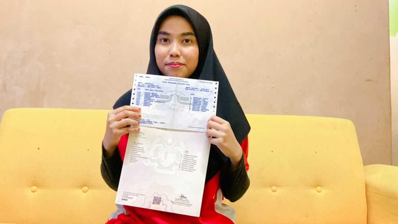 Nor Adilla Ramli holds up her certificates for the SPM examination, which she took despite being told to stop attending school as she is stateless. 
