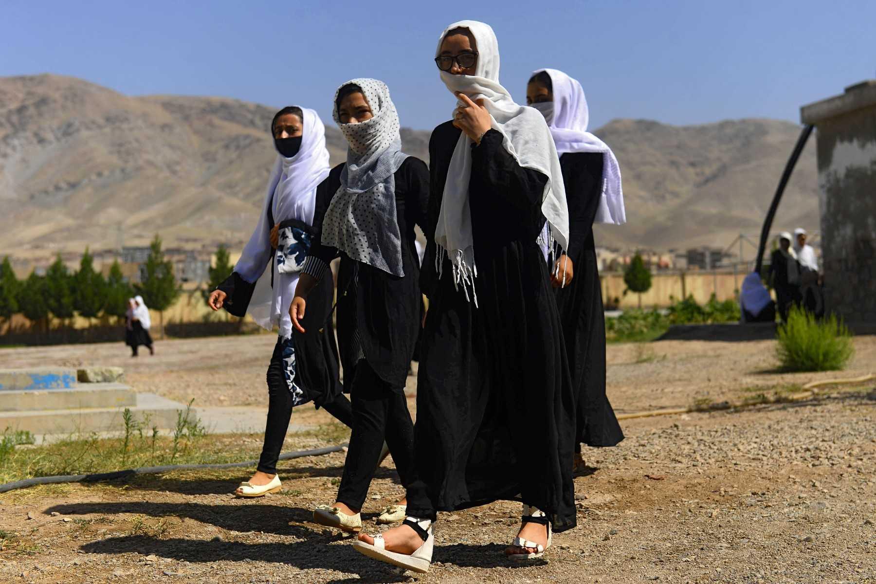 Afghan girl students cover their faces with scarfs as they walk inside the compound of their school after it was reopened, which was earlier closed due to the Covid-19 coronavirus pandemic, in Herat on Aug 23, 2020. Photo: AFP