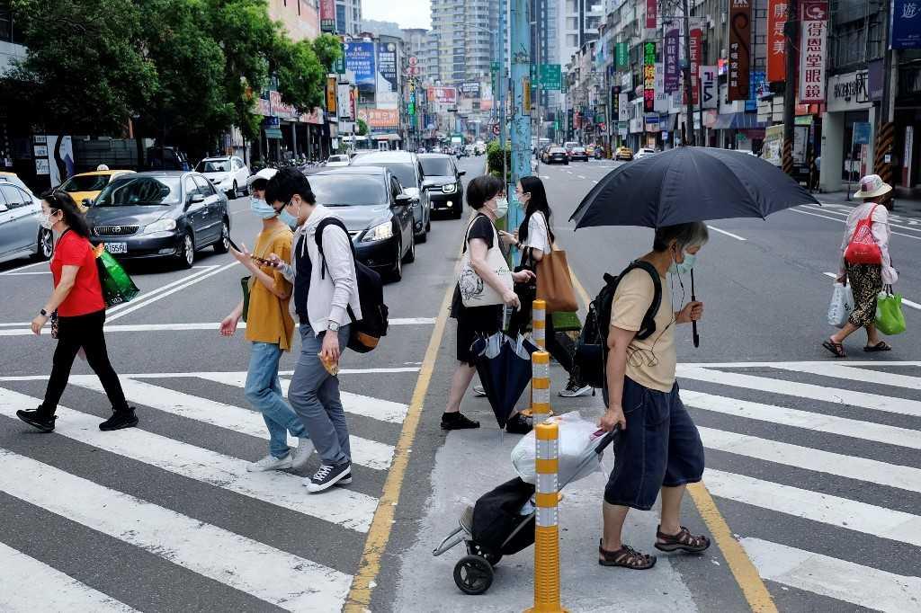 Pedestrians, wearing face masks after Taiwan bumped up its alert level in some locations following a new wave of Covid-19 infections, cross a street in New Taipei City on May 15, 2021. Photo: AFP