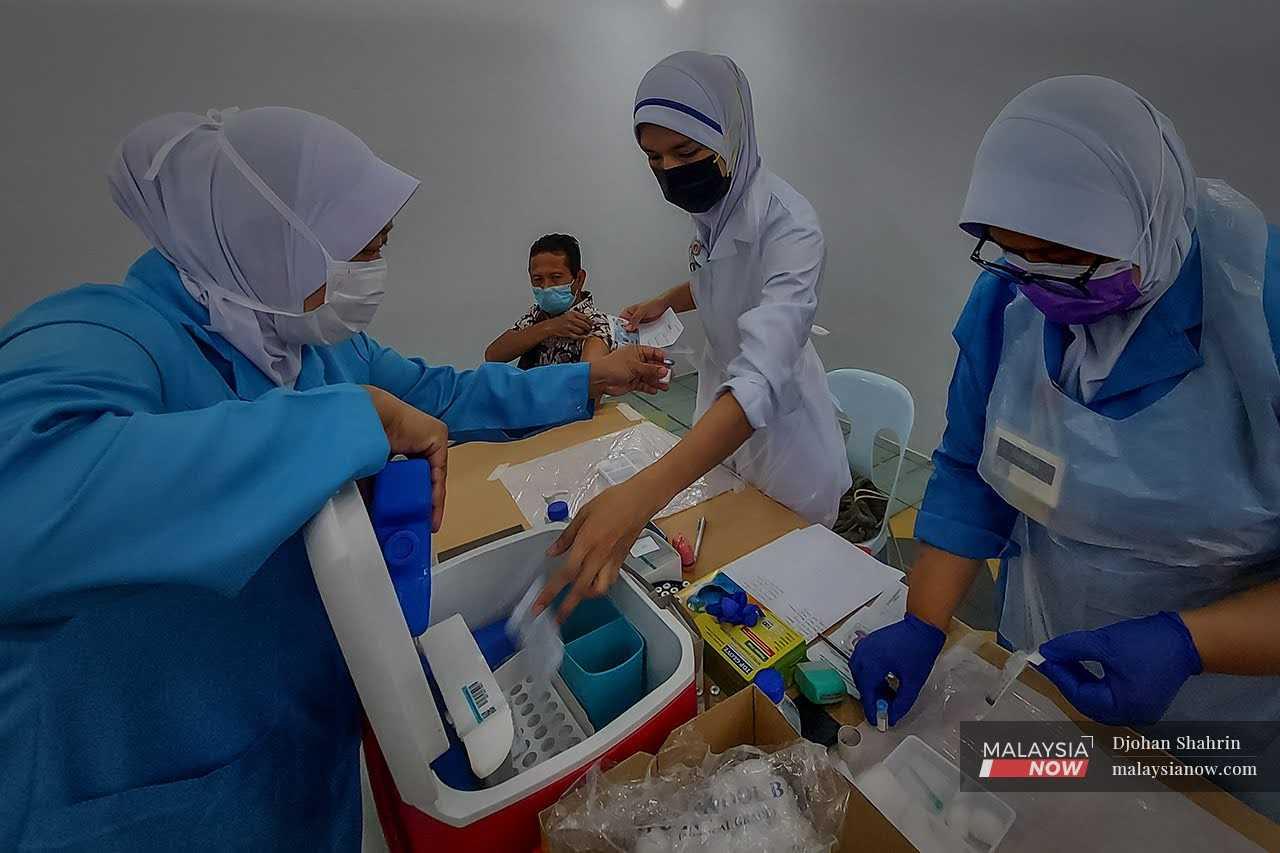 Jururawat dan petugas kesihatan menyiapkan vaksin Covid-19 untuk diberikan kepada gelandangan Pusat Transit Gelendangan Kuala Lumpur di Anjung Kelana, Taman Desa, Kuala Lumpur pada Jun 2021.
