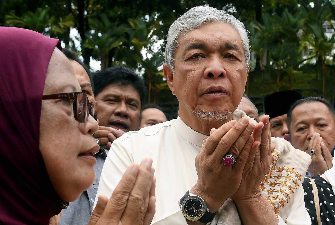 Umno president Ahmad Zahid Hamidi says a prayer of thanks with his supporters outside the Shah Alam High Court after his acquittal today of 40 counts of corruption related to the foreign visa system. Photo: Bernama