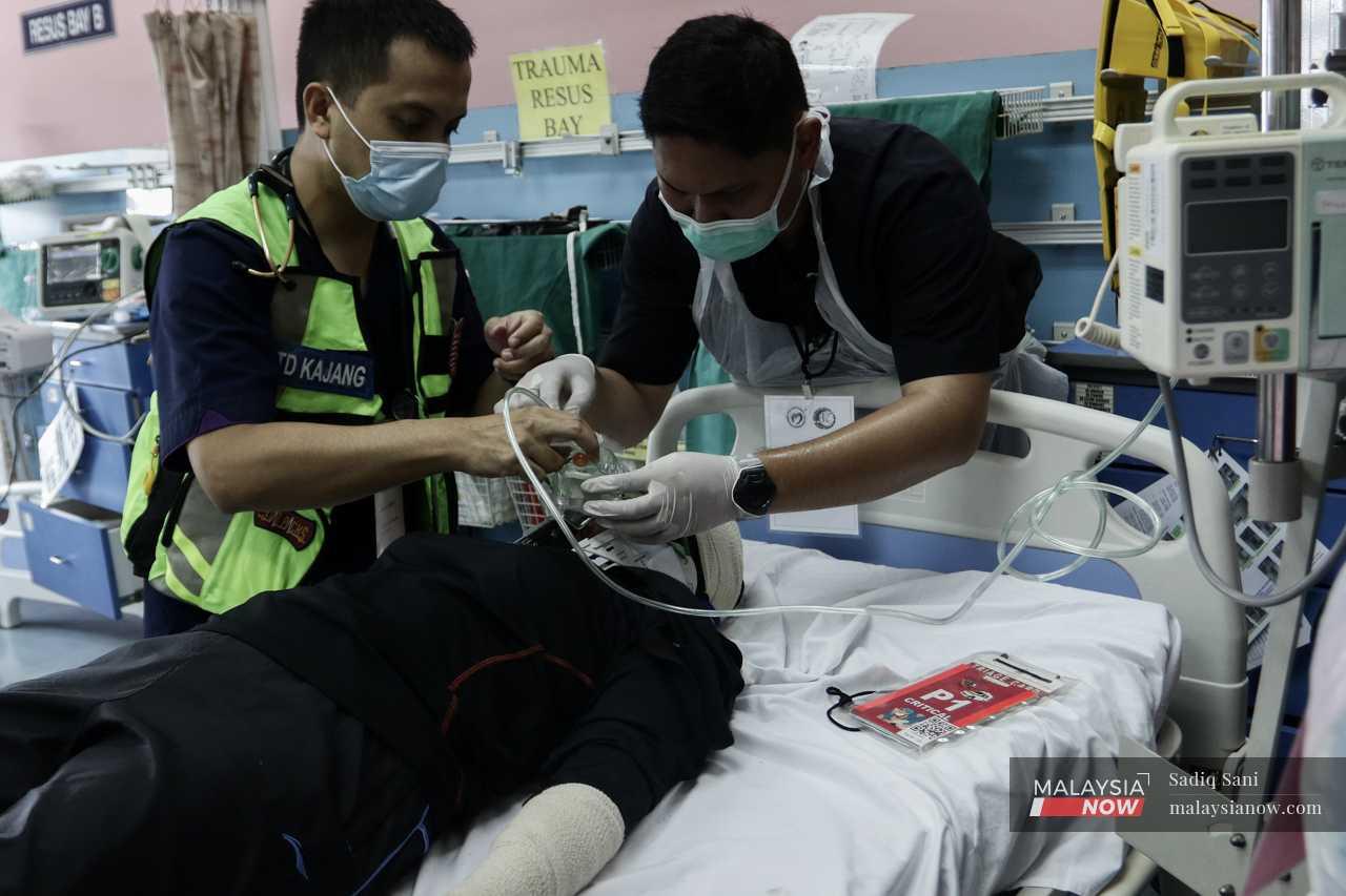Medical officers attend to a volunteer presenting with more critical injuries, inserting an oxygen tube to help him breathe. 