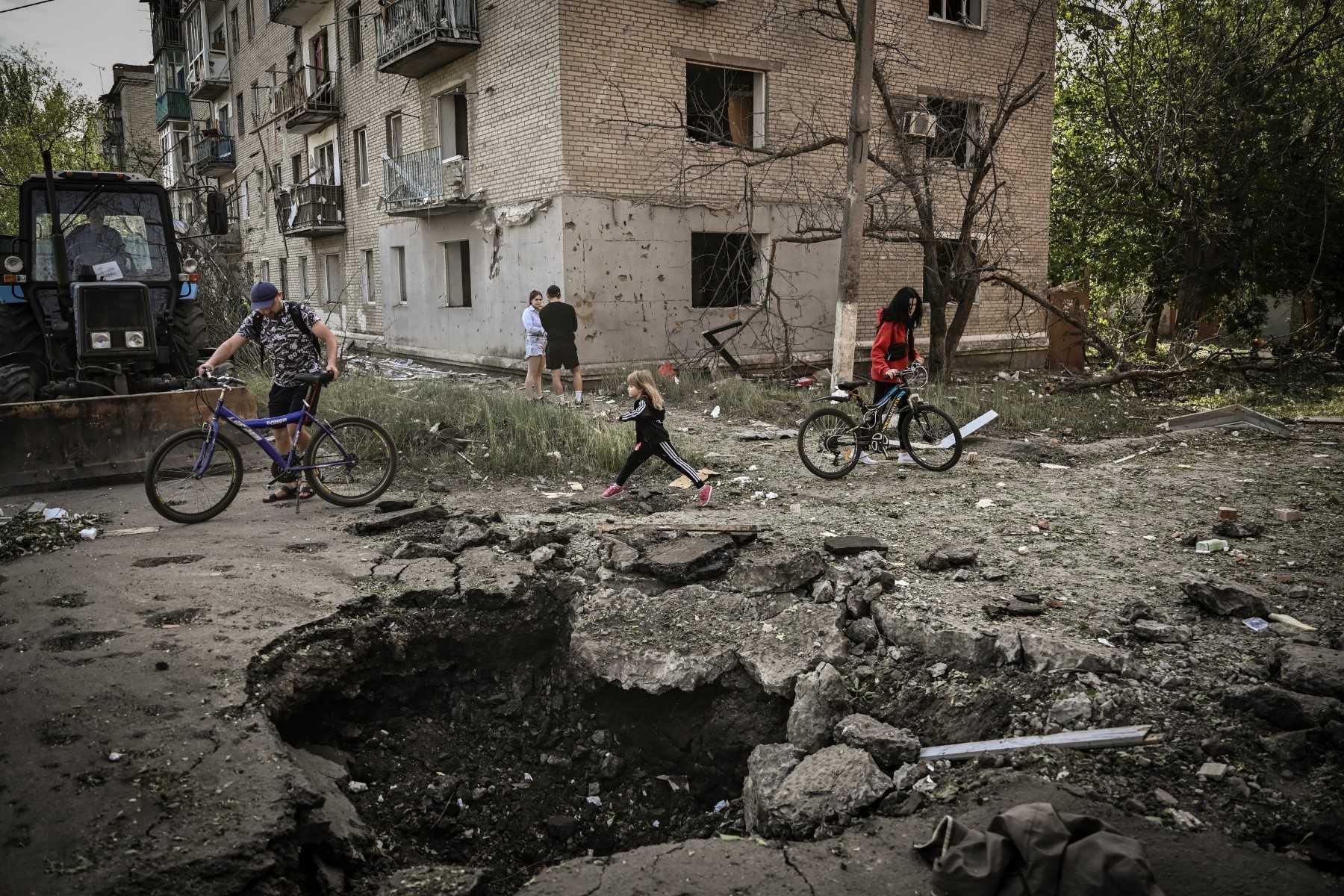 A young girl walks by a crater in front of a damaged apartment building after a strike in the city of Sloviansk at the eastern Ukrainian region of Donbas on May 31, amid the Russian invasion of Ukraine. Photo: AFP