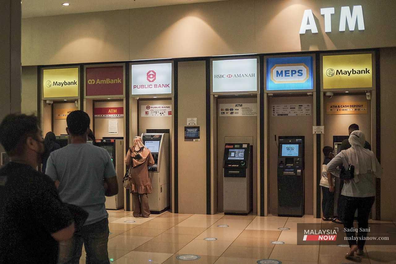 Orang ramai beratur ketika menggunakan mesin ATM di sebuah pusat beli-belah di Putrajaya.