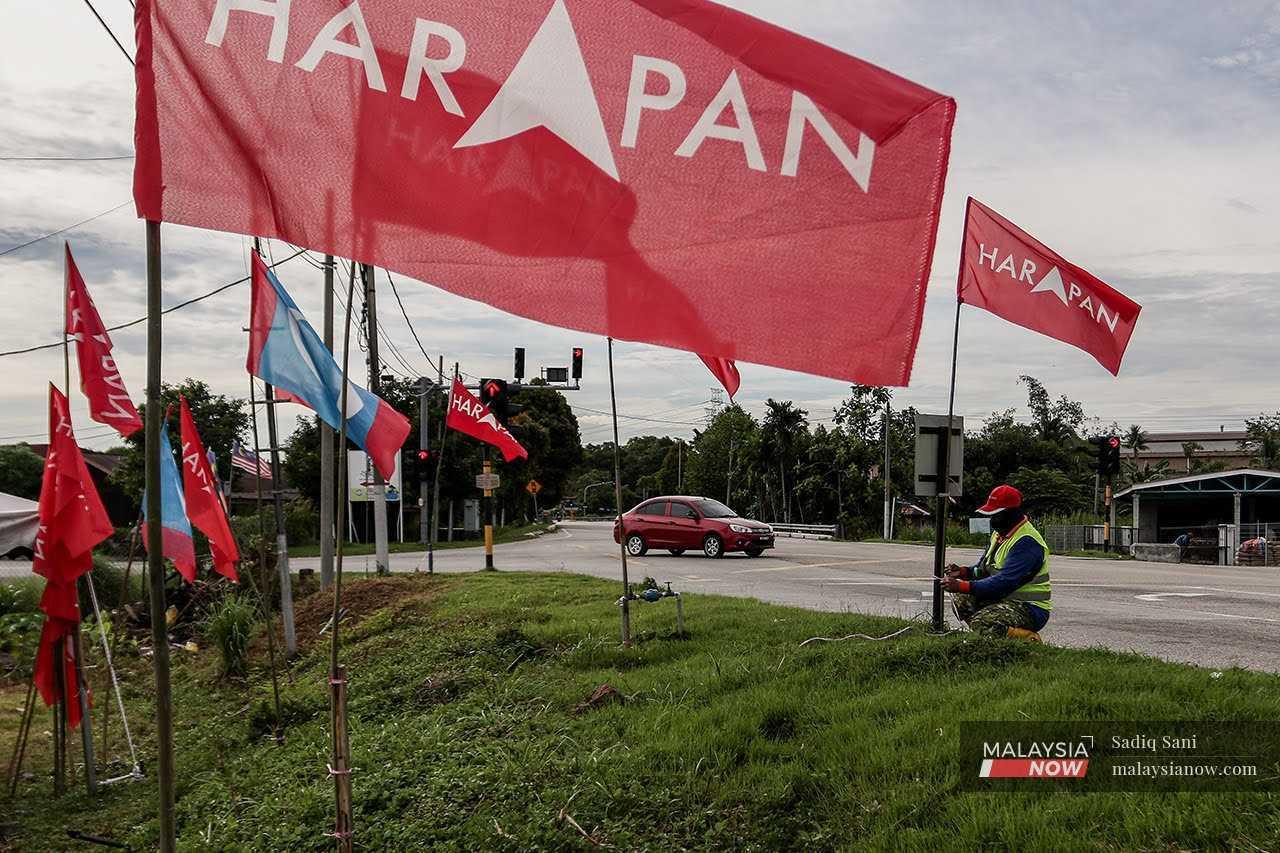 Petugas pilihan raya mengibarkan bendera Pakatan Harapan dan PKR di Jalan Tanjung Kling menjelang Pilihan Raya Negeri Melaka pada November tahun lalu.