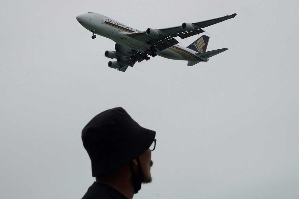 A man watches as a Singapore Airlines plane approaches for landing at Changi International Airport in Singapore, Aug 23, 2020. Photo: AFP 