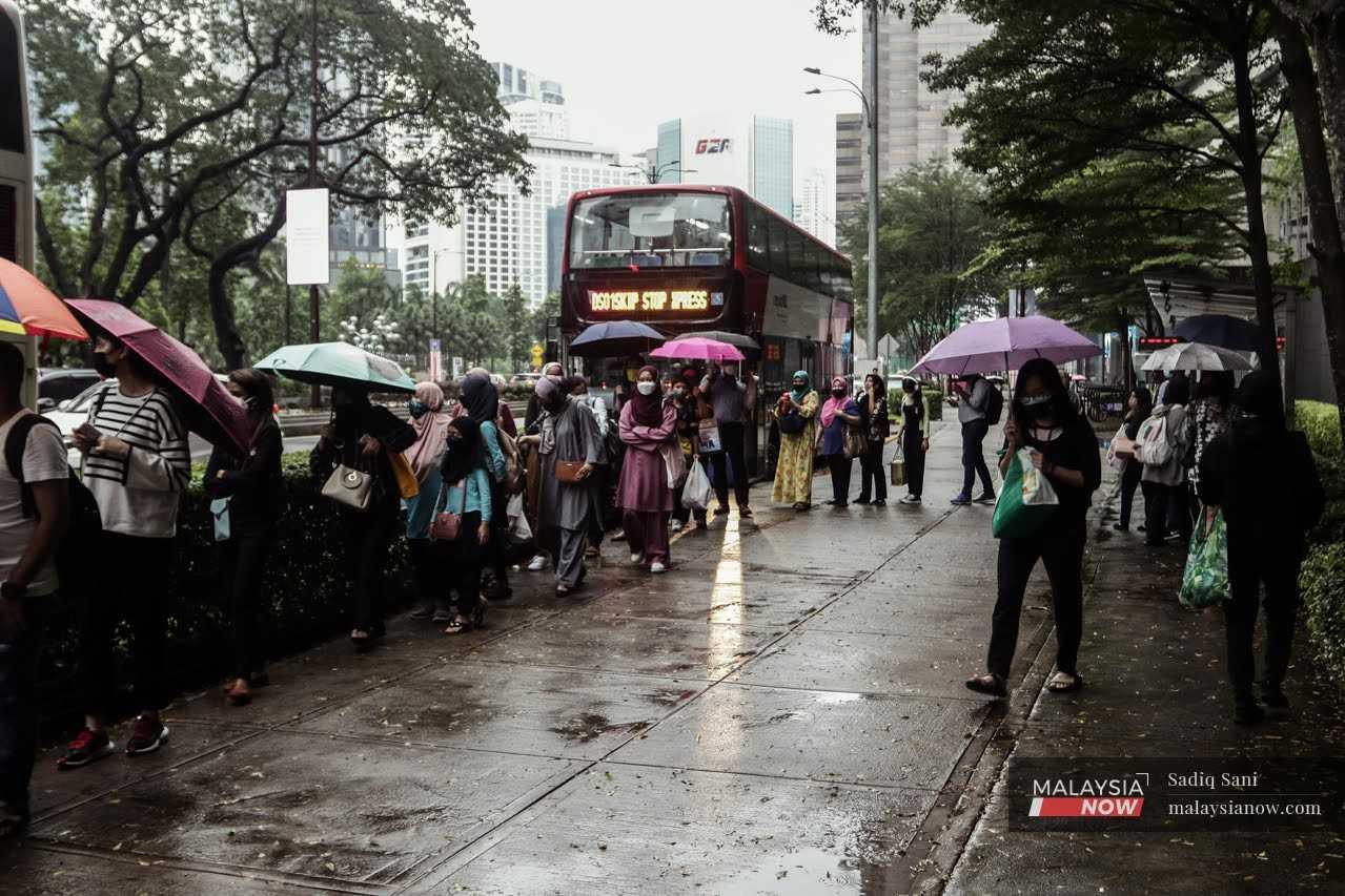 Orang ramai memakai payung ketika mengharungi hujan di pusat bandar Kuala Lumpur.