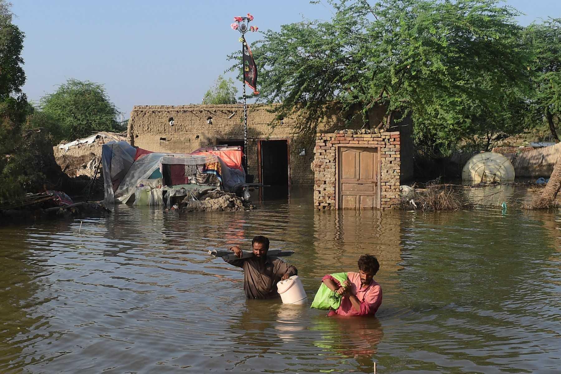 Flood affected people carry belongings out from their flooded home in Shikarpur, Sindh province, on Aug 31. Photo: AFP 